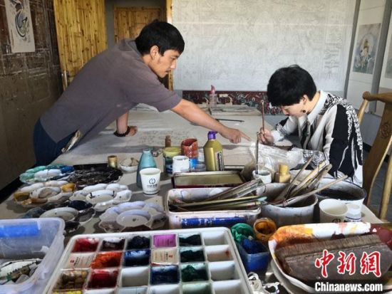 圖為2020年8月下旬，敦煌“80后”畫家張杰龍(左)在為云南麗江“學生”莫北講解敦煌壁畫的繪畫技巧?！●T志軍 攝