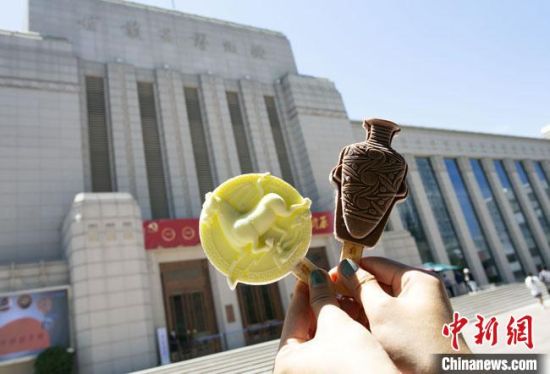 2021年7月30日，游客手拿“銅奔馬”“彩陶瓶”造型的雪糕，在甘肅省博物館前拍照打卡?！「哒?攝