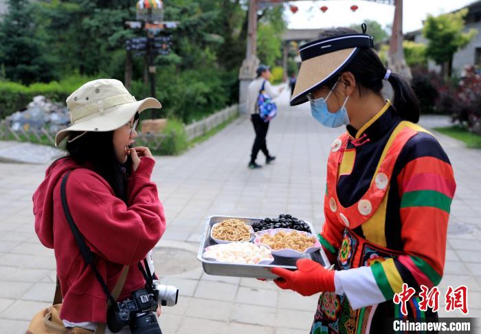 圖為身穿土族服飾的女性介紹當(dāng)?shù)靥厣〕??！⊙Φ?攝