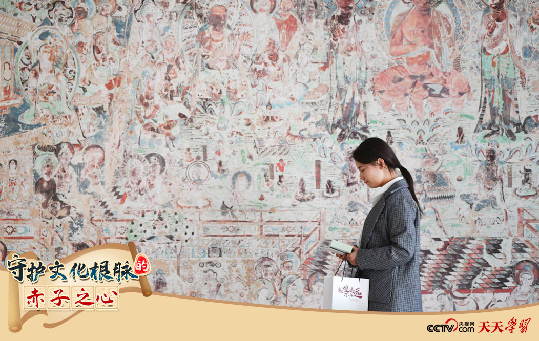 2023年4月25日，敦煌研究院文物數(shù)字化保護團隊創(chuàng)意營銷人員廖雪婷從一幅高保真復制壁畫前走過。