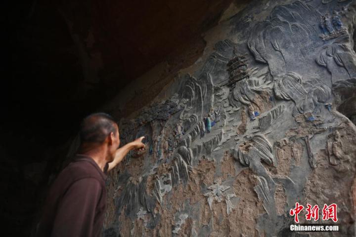 7月15日，甘肅省平?jīng)鍪袥艽h百里石窟長(zhǎng)廊羅漢洞石窟內(nèi)，該窟文保員郭建平介紹窟內(nèi)石刻彩繪壁畫。郭建平家中三代人曾自發(fā)保護(hù)羅漢洞石窟。羅漢洞石窟遺存40余個(gè)窟龕，以北魏至清代風(fēng)格為主。中新社記者 李亞龍 攝