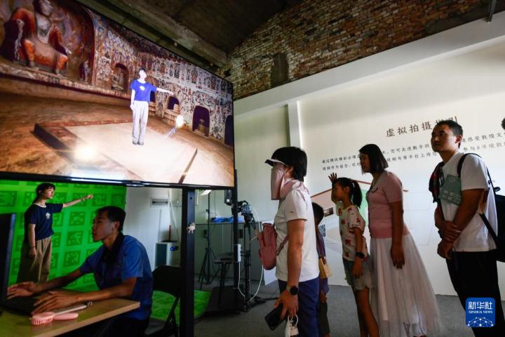 7月22日，游客體驗“尋境敦煌——數(shù)字敦煌沉浸展”后，在虛擬演播廳拍攝一段真人與洞窟虛擬場景交互的視頻。新華社記者 郎兵兵 攝</p>
<p>