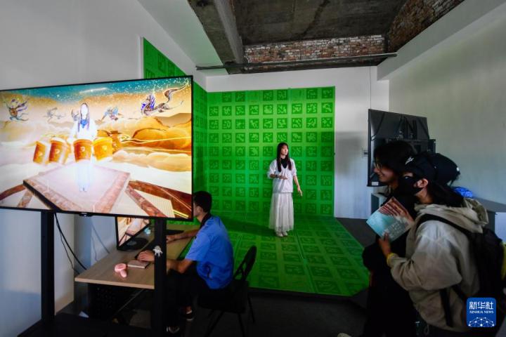 7月22日，游客體驗“尋境敦煌——數(shù)字敦煌沉浸展”后，在虛擬演播廳拍攝一段真人與洞窟虛擬場景交互的視頻。新華社記者 郎兵兵 攝</p>
<p>